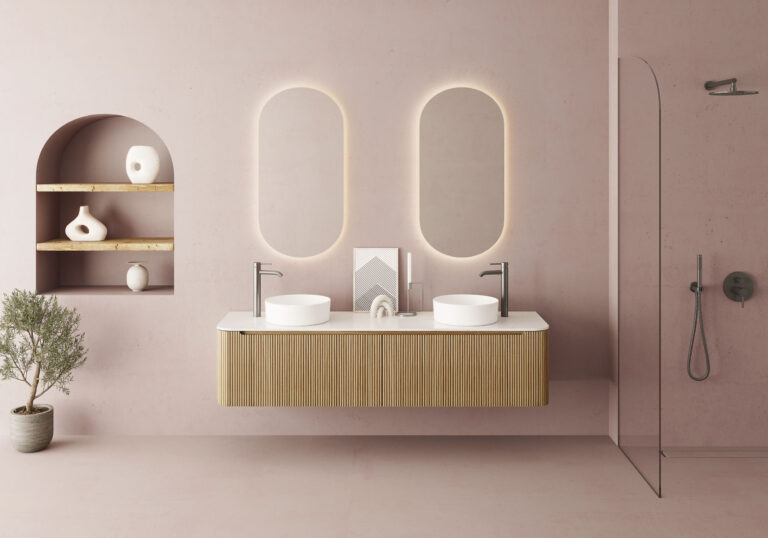 Baño moderno con mueble suspendido de madera clara y lavabos dobles, acompañado de espejos ovalados con retroiluminación y ducha de vidrio transparente.